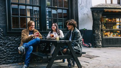 students sitting on a bench, having beverages and enjoying the weather outside