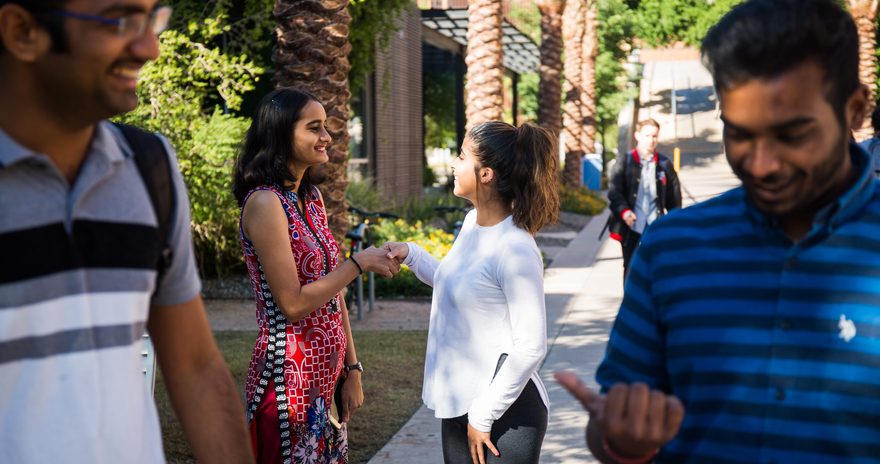 Two students shhaking hands on campus