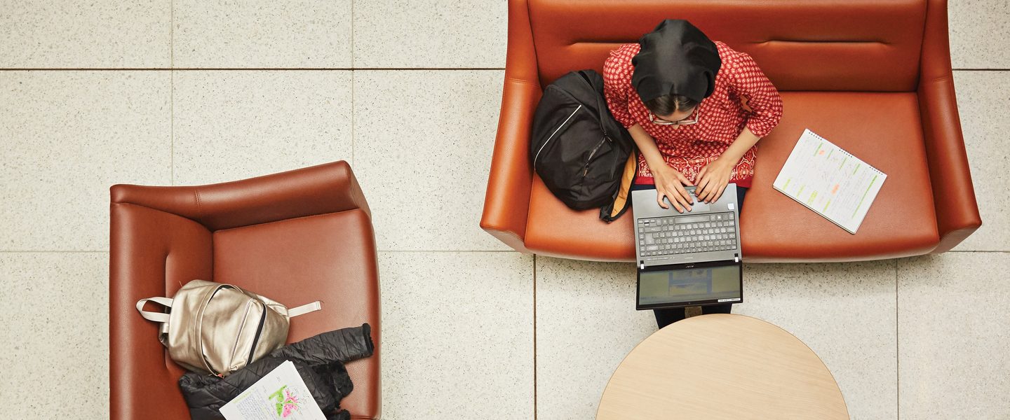 Student working on laptops and pads on sofas