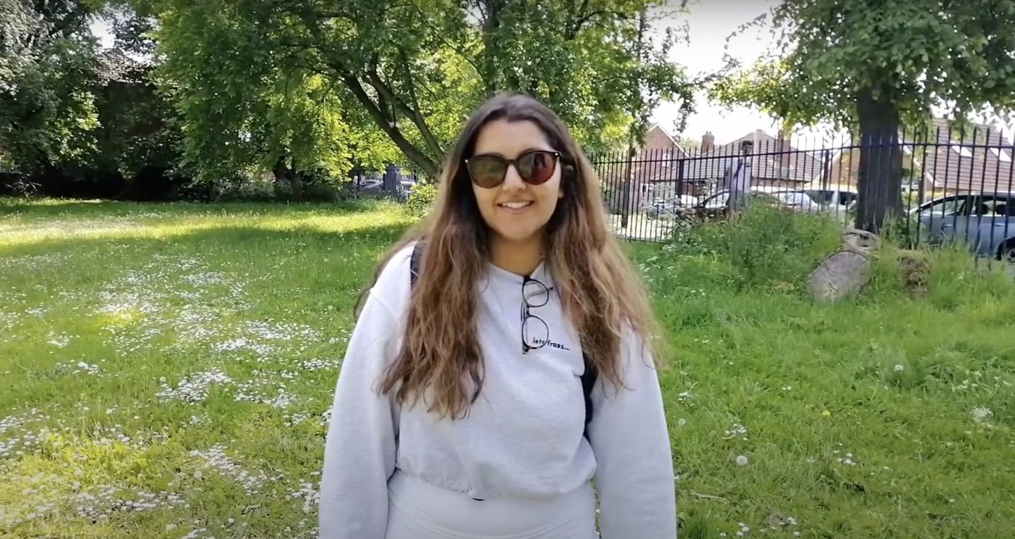 student sitting next at the riverside and smiling to the camera