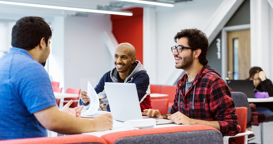 A group of students having a conversation while studying in the library