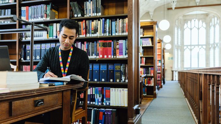 University of Bristol student writing at the library