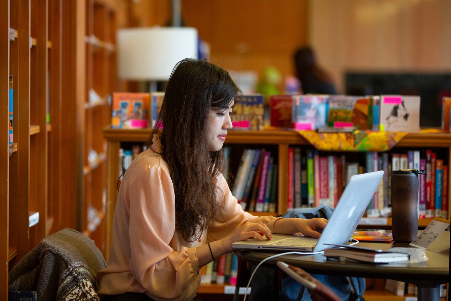 University of Oregon student in the library studying on their laptop