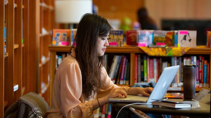 Oregon student in the library utilising their laptop for study purposes