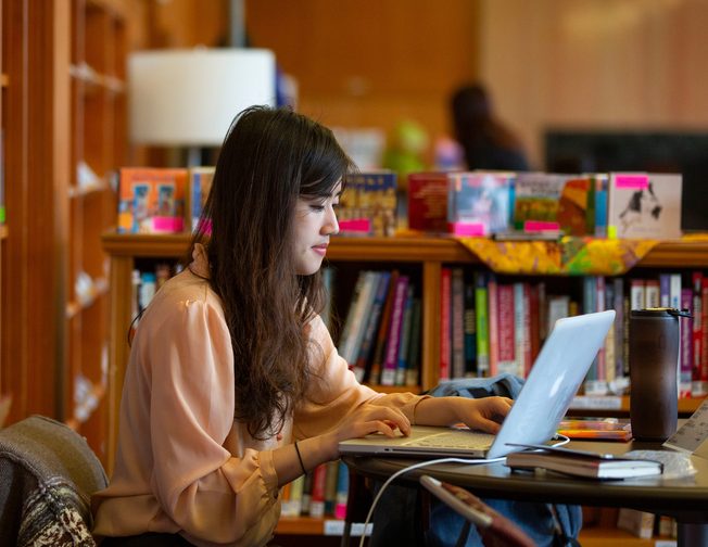 Oregon student in the library utilising their laptop for study purposes