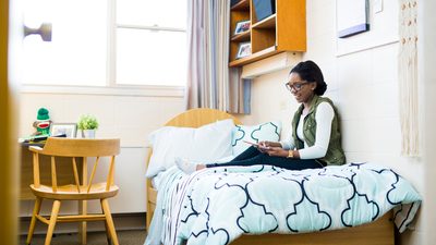 Student siting on her campus dorm's bed at the U of A