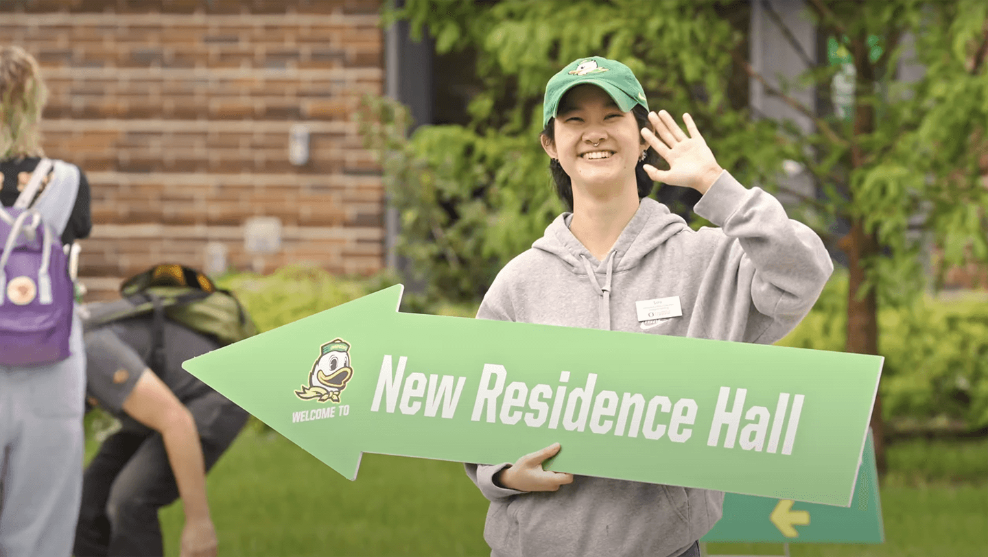 A UO student holding a sign leading to new residence hall